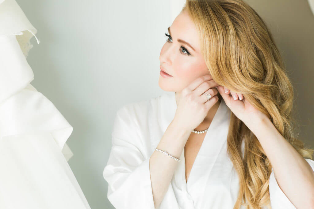 Bride getting ready wearing a white robe. 