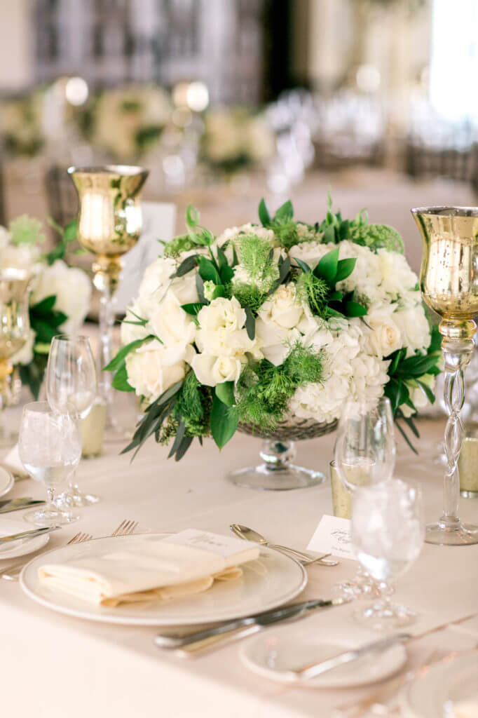 Center pieces of roses and greens in a silver base. 