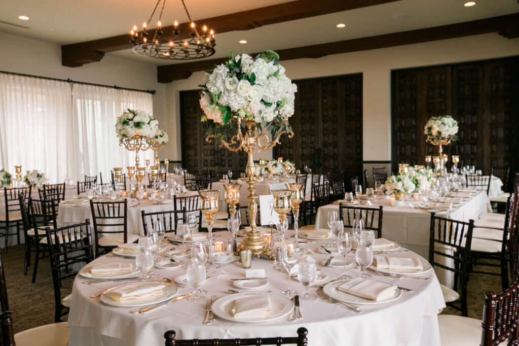 Tall center pieces in a wedding with white roses and greenery 