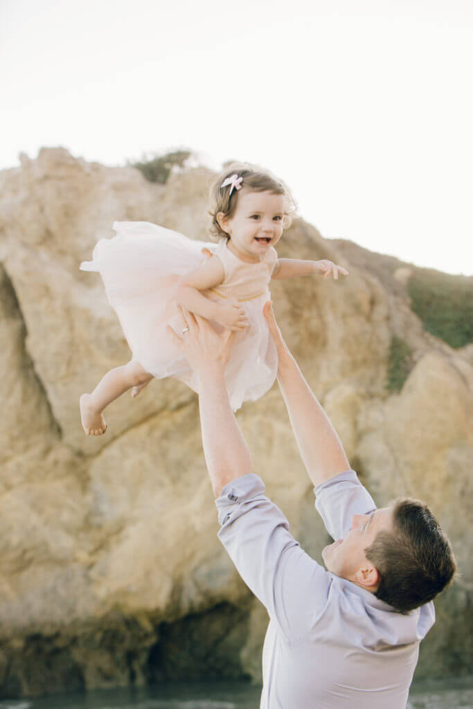 dad and little girl bonding on the beach smiling 