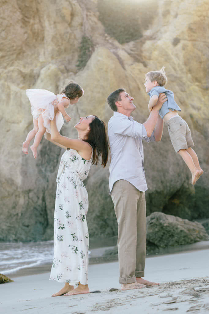 family of four on the beach wearing pastel tones 