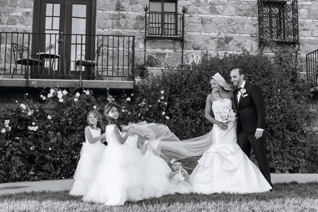 Couple looking at the flower girls under the veil of the bride