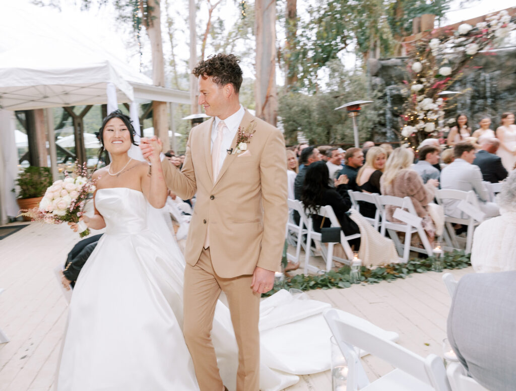 Groom Looking at his beautufil bride after marrieng her, he is wearing a beige tuxedo with a pink tie