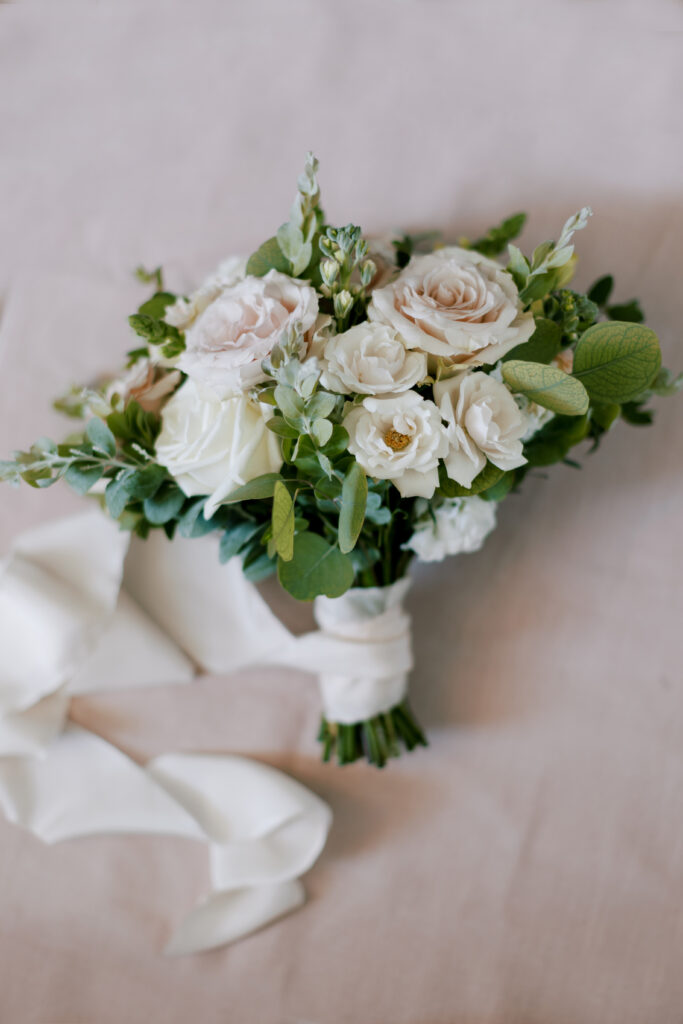 wedding florals with a silk white ribbon over a pink flat lay