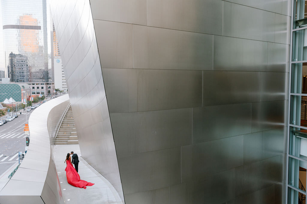 Couple at Disney Hall in Down town los angeles she is wearing a red dress and he is wearing a dark jacket