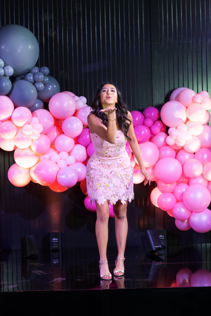 Young female wearing a pink dress sending a kiss. 