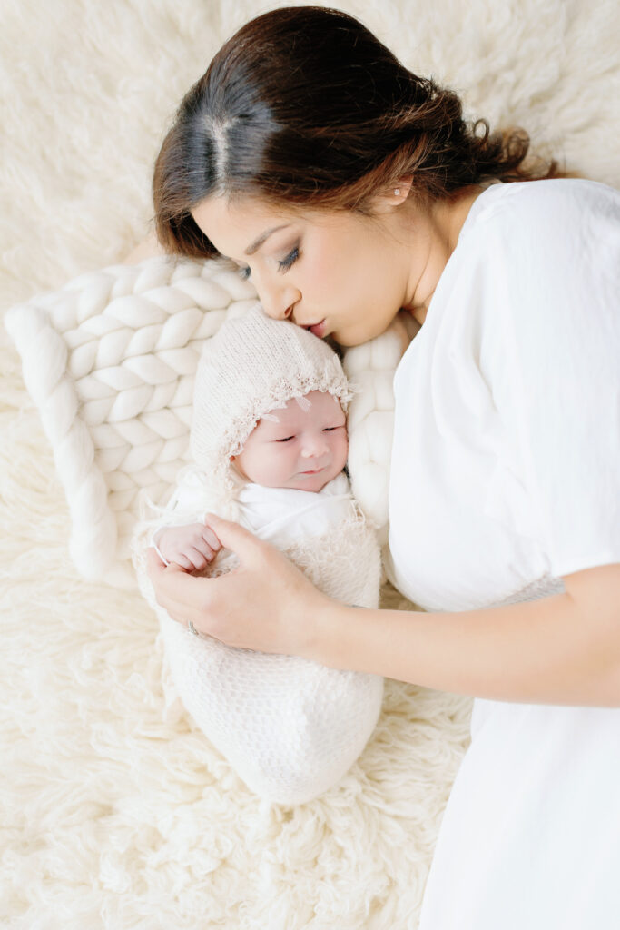 mother kissing her baby girl bot wearing white