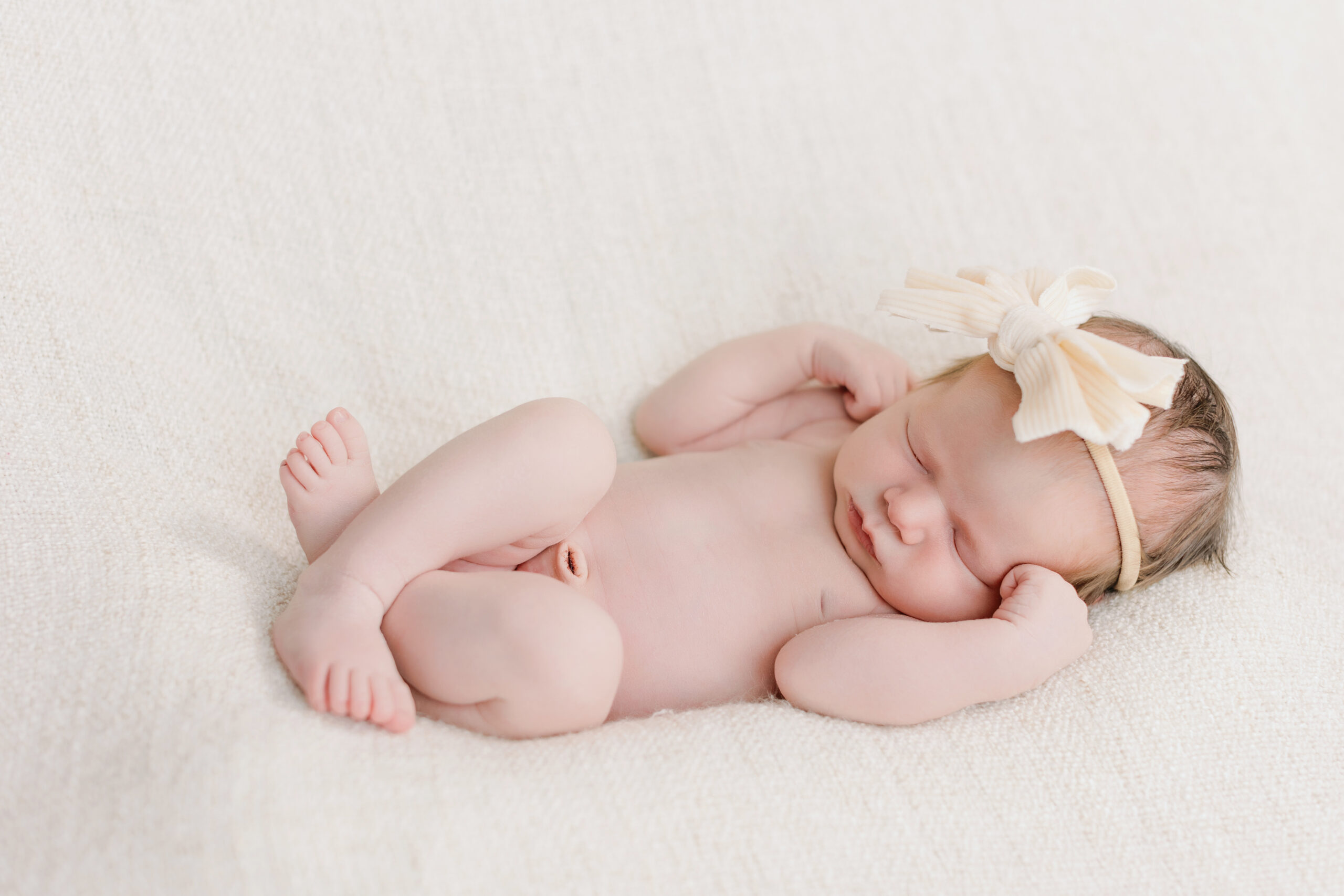 Newborn baby girl sleeping vertical on a white blaket