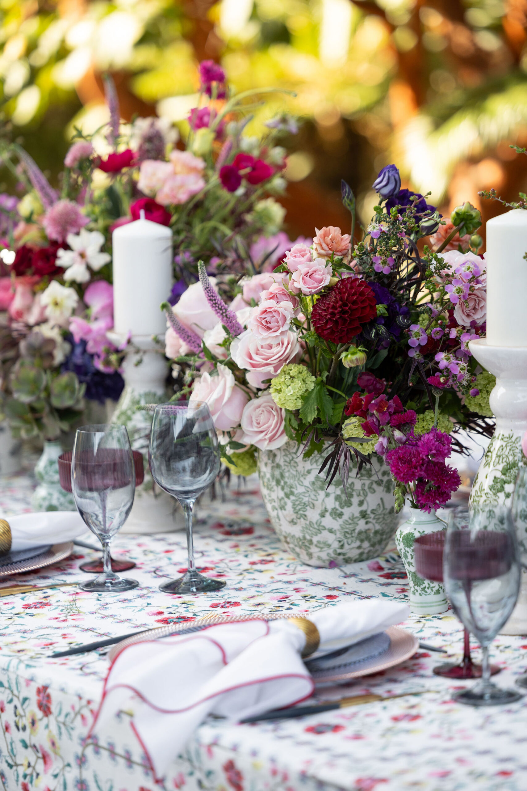 Colorful luxury wedding tablescape with pink, fuchsia, purple, and blush florals, patterned linens, candlelight, and elegant place settings.colors