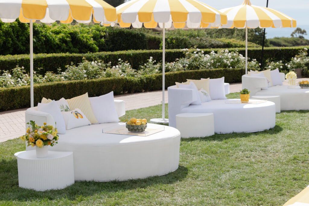 White lounge daybeds under yellow striped umbrellas at a Sonia Sharma Events engagement party