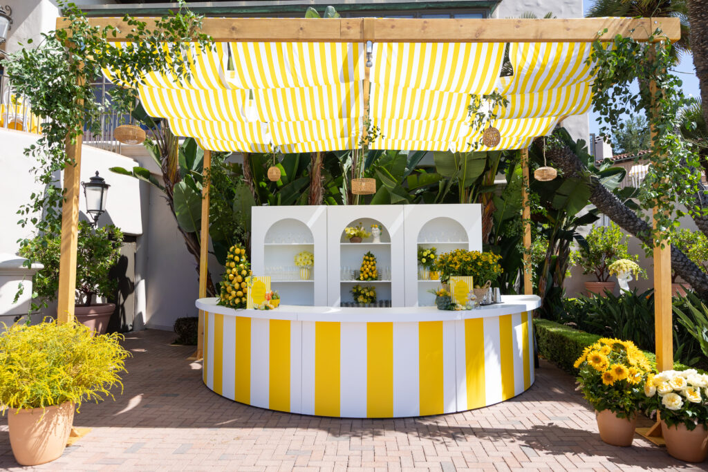 Custom striped bar with lemon topiaries and yellow florals by The Empty Vase at a Pelican Hill engagement party