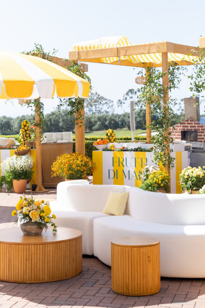White curved lounge sofa near a striped Frutti di Mare food station at a Sonia Sharma Events party in Newport Coast