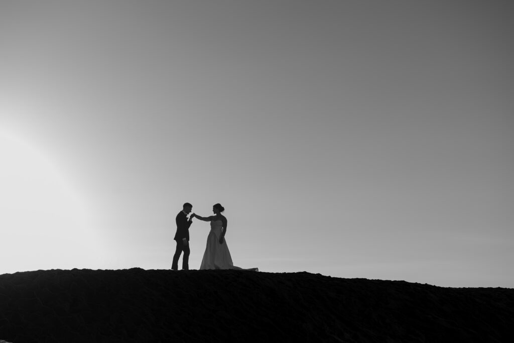 Artistic black-and-white silhouette of the bride and groom against the open sky on Huntington Beach.