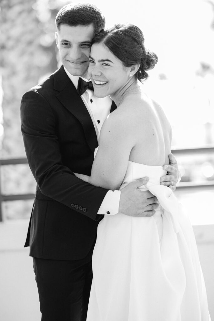 Natural black-and-white portrait of a smiling bride and groom embracing on their wedding day