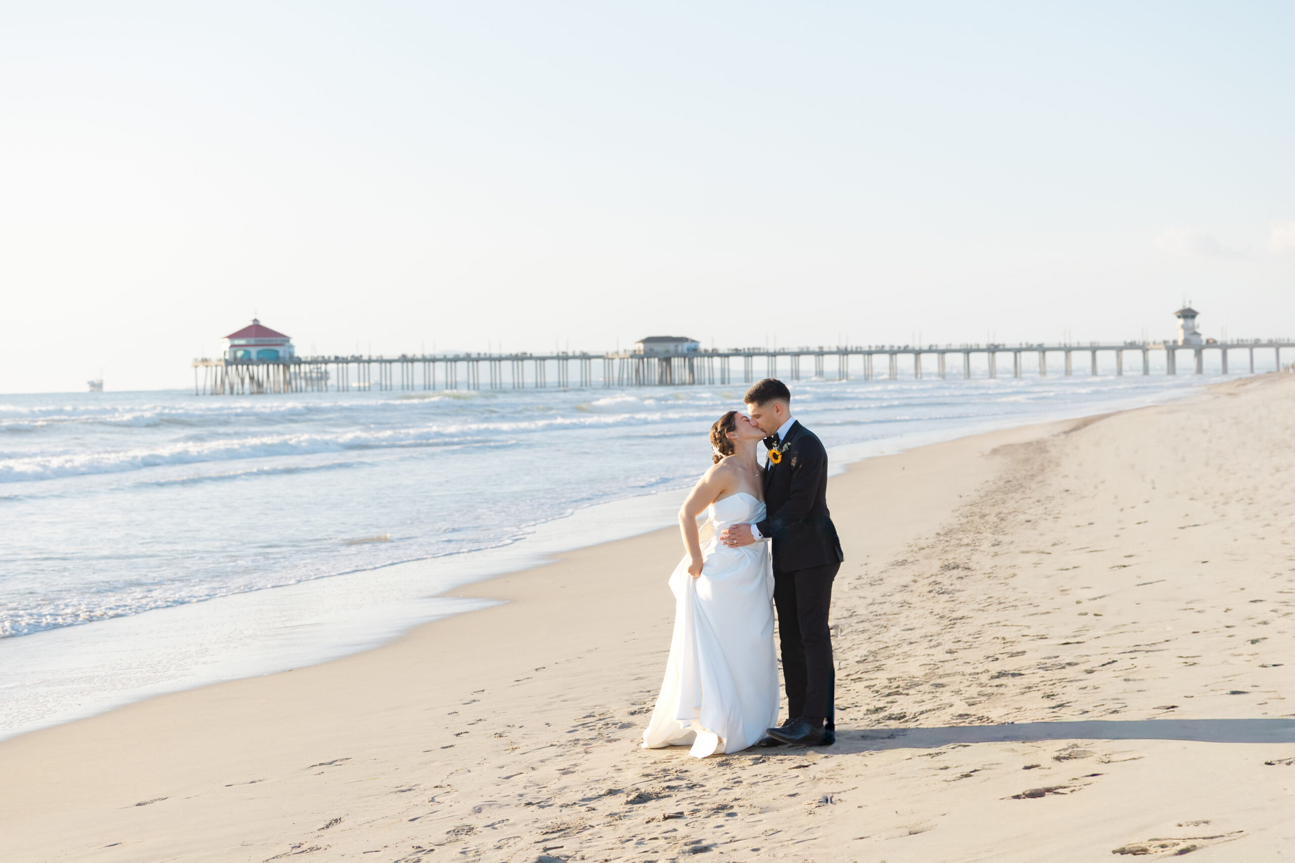 Bride and groom on the beach near The Waterfront Beach Resort with Huntington Beach Pier in the background