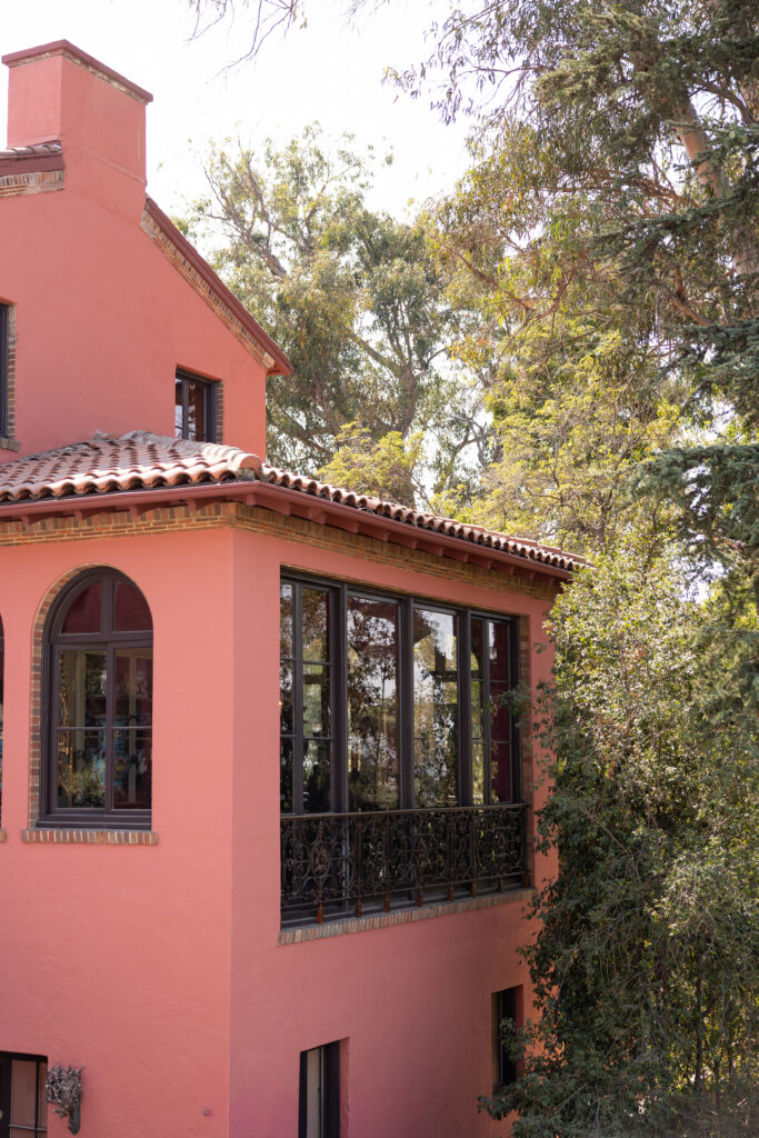 Exterior view of the historic coral-colored Paramour Estate surrounded by mature trees.